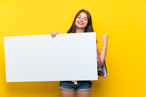 Caucasian girl in colorful dress over isolated yellow background holding an empty white placard for insert a concept - Фото, зображення