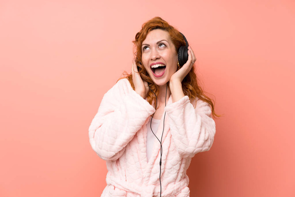 Redhead woman in dressing gown listening music - Photo, Image