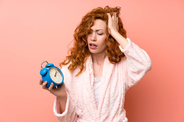 Redhead woman in dressing gown holding vintage clock - 写真・画像