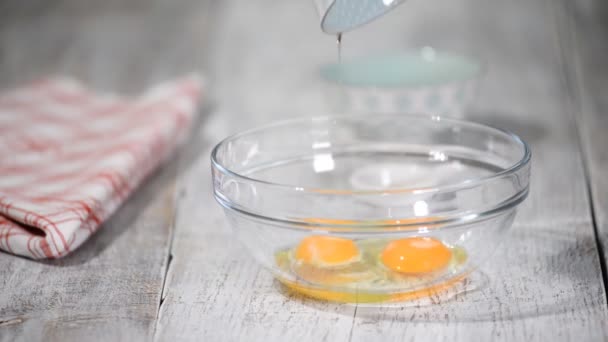 Las manos femeninas batir con la batidora los huevos con azúcar para hacer la masa. Huevos y azúcar en el tazón
. - Imágenes, Vídeo