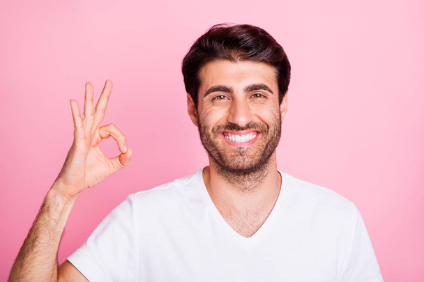 Portrait of positive cheerful middle eastern man show okay sign enjoy promotions recommend ads wear white clothes isolated over pink color background - 写真・画像