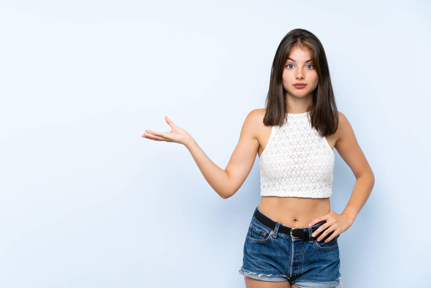 Young woman over isolated blue background making doubts gesture - Photo, Image
