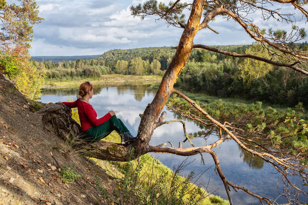 Young girl on a nature background, on a rock by the river. landscape, journey to  nature - Foto, afbeelding