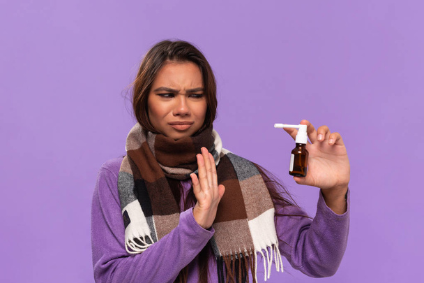 Досить афро-американська дівчина в светрі і затишний перевірений шарф чхає стоячи ізольовано на фіолетовому фоні. Застуда взимку
. - Фото, зображення
