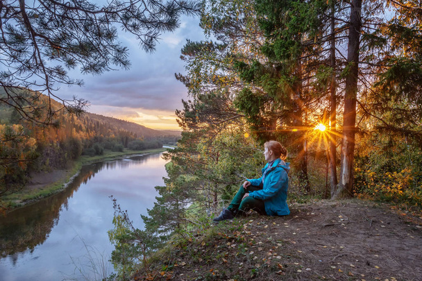 autumn landscape. Young girl tourist sitting on the bank of the river,  looking at the river. camping in the fall - Foto, Imagem