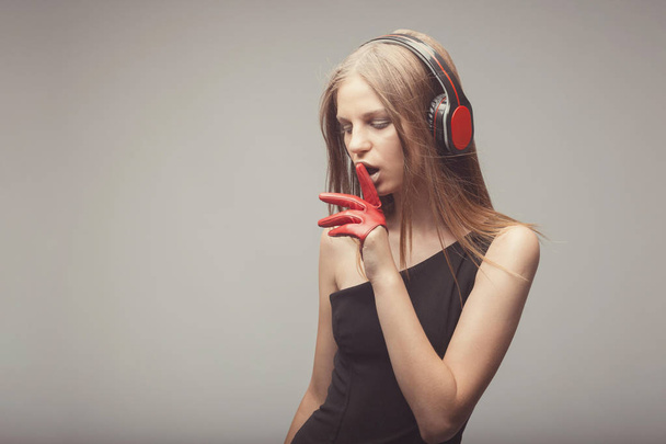 Όμορφο κορίτσι μόδας ακούτε μουσική με ακουστικά, φορώντας κόκκινο - Φωτογραφία, εικόνα