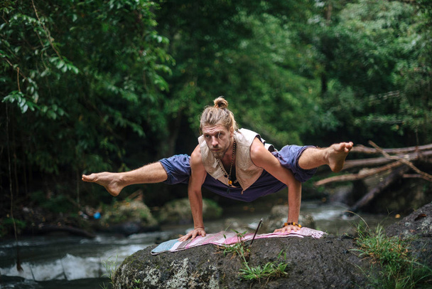 Yoga practice and meditation in nature. Man practicing near river - Zdjęcie, obraz