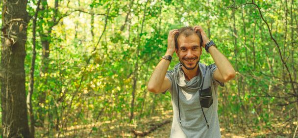 A portrait of a handsome man with beard against the background of green trees in the park. - Fotoğraf, Görsel