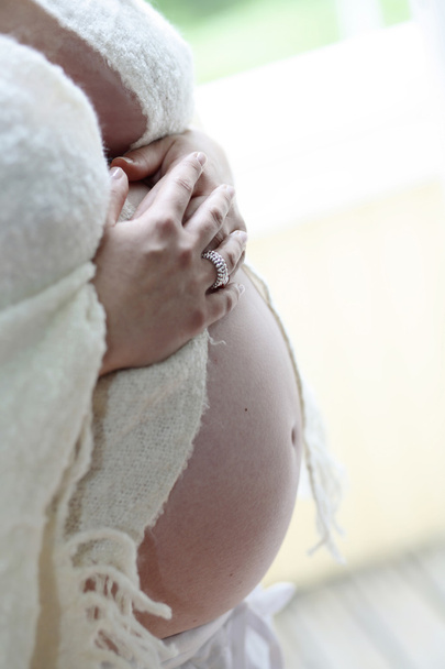 Woman holding her bare pregnant belly in - Fotoğraf, Görsel