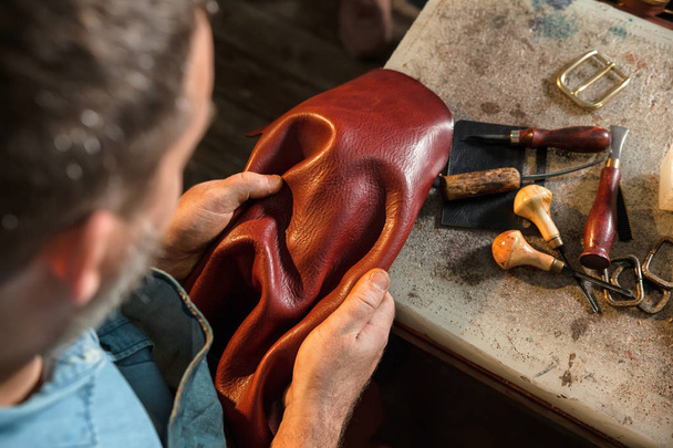 Craftsman touching leather, close-up. A raw material, stuffs and preparation of leather craft work - Фото, изображение