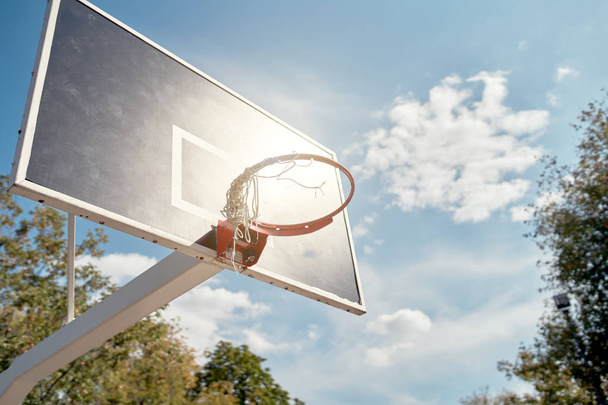 Image of basketball hoop against blue, cloudy sky on summer day. - Фото, изображение
