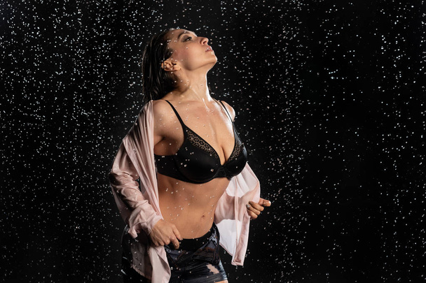 beautiful sensual woman wearing lingerie posing in wet Studio on black background - Foto, afbeelding