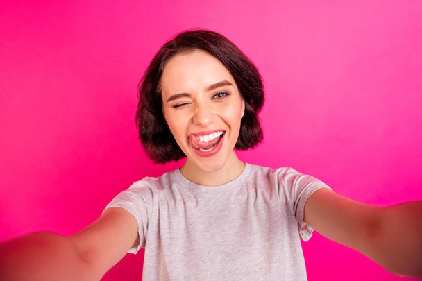 Self portrait of charming cute nice flirty playful girlfriend licking her upper lip while shooting herself taking selfie isolated over fuchsia vivid color background - Foto, Imagem