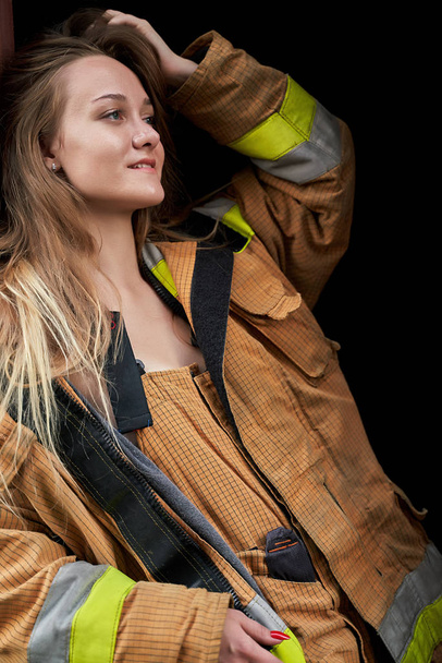 Image of young firefighter woman in overalls on black empty background. - Photo, Image