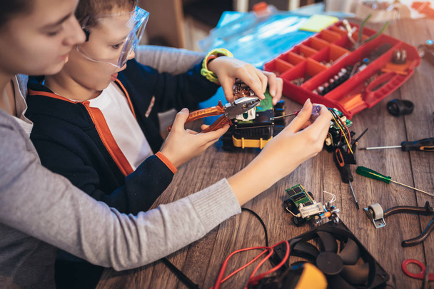 Feliz sonriente chico y chica construye juguete técnico y hacer robar
 - Foto, Imagen