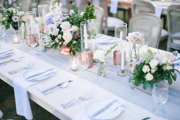 Beautiful outdoor table setting with floral decorations and candles for a wedding reception - Фото, зображення