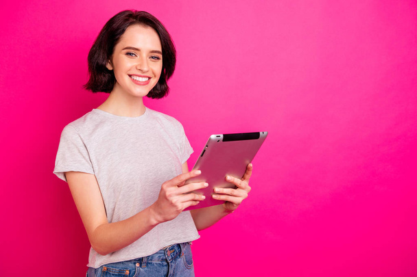 Portrait of cheerful excited freelancer using tablet searching news wearing white t-shirt isolated over pink fuchsia background - Foto, immagini