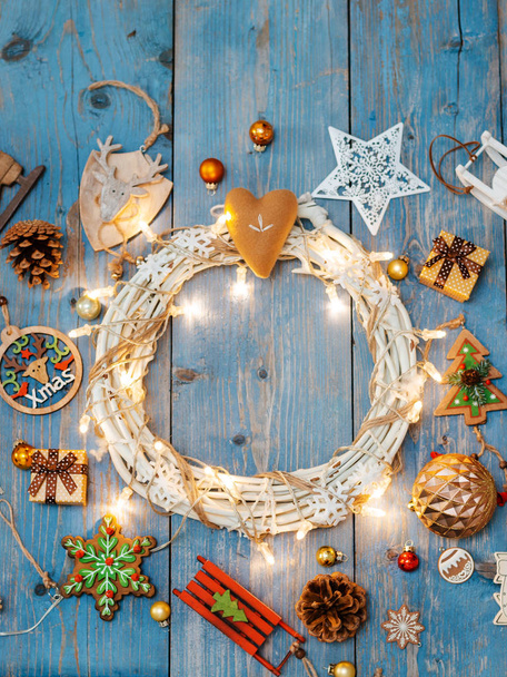 Nowy rok dekoracje wokół świątecznego wieńca na niebieskim drewnianym tle. - Zdjęcie, obraz