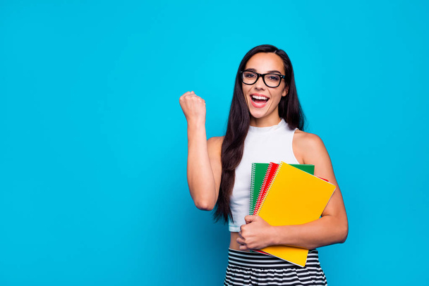 Photo of pretty lady holding study book in arms diligent student celebrating best exam result wear specs white tank-top and striped skirt isolated blue color background - Φωτογραφία, εικόνα