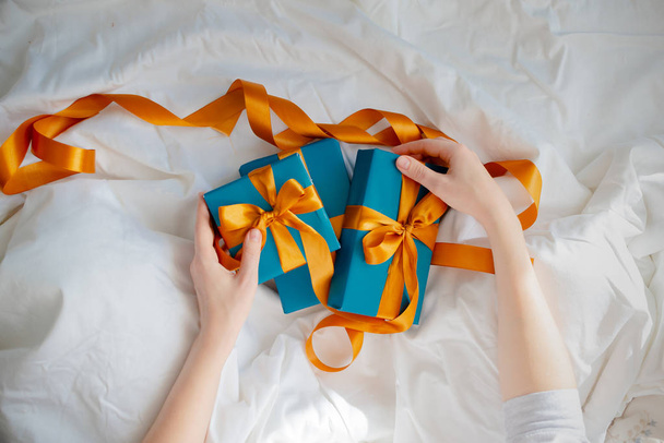 Руки женщины держат подарки у кровати. Новый год и Рождество
 - Фото, изображение