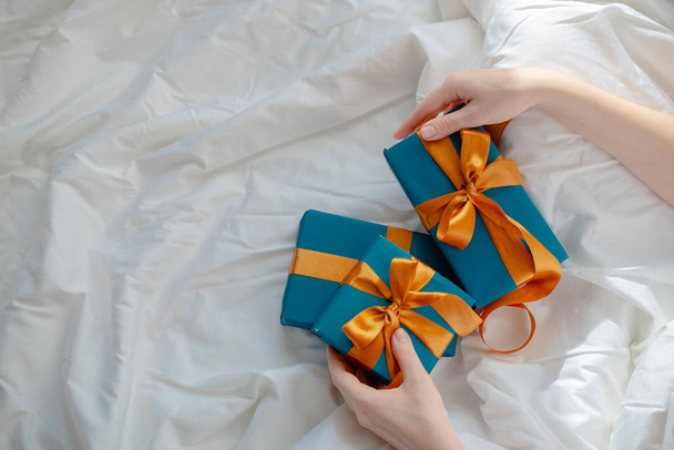 Female hands holding presents bedside. New year and christmas co - Φωτογραφία, εικόνα
