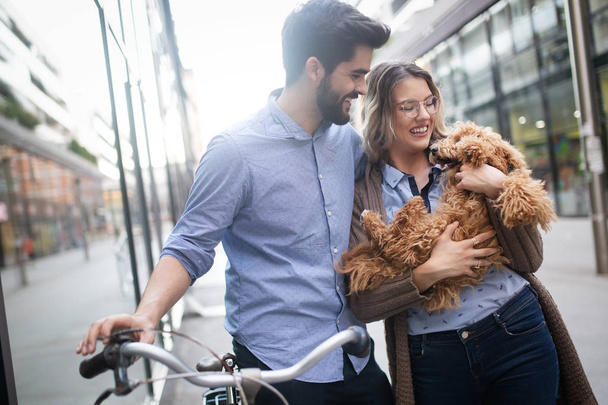 Beautiful young couple walking dogs and bicycles outdoors in city - Foto, Imagen