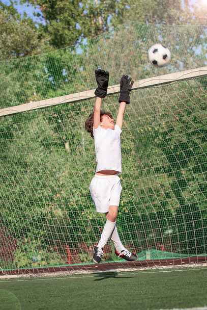 Summer soccer tournament for young kid. Football club. Emotions and joy of the game. Young goalie. Boy goalkeeper in football sportswear on stadium with ball. Sport concept. selective focus - Foto, imagen
