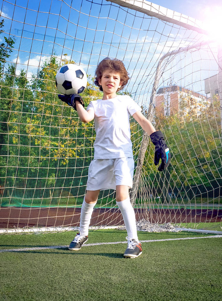 Little boy with his dad playing football on soccer pitch. Kid football player preparing to take a shot on a field. Young goalkeeper on an outdoor court standing in the football gate. - Photo, Image