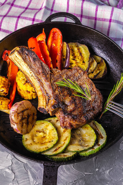 Szaftos steak grillezett zöldségekkel, öntöttvas serpenyőben. Életstílus. Felülnézet - Fotó, kép