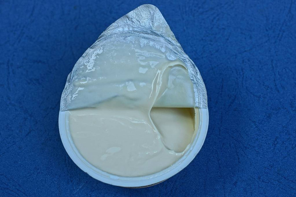crème sure blanche dans une boîte ronde en plastique se tient sur une table bleue
 - Photo, image