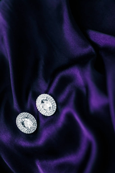 Lusso orecchini di diamanti su tessuto di seta viola scuro, glam vacanza
 - Foto, immagini
