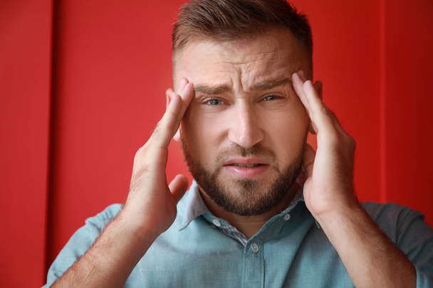 Young man suffering from headache on color background - Foto, Bild