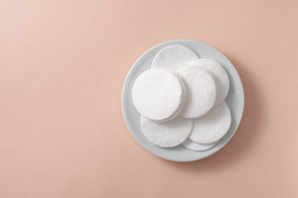 A pile of cotton pads in a plate on a pink background - Valokuva, kuva