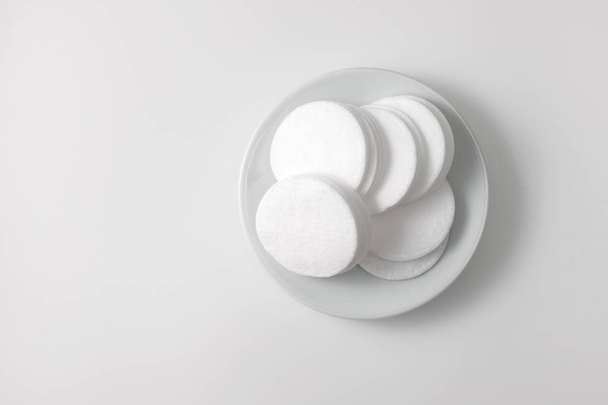 A pile of cotton pads in a plate on a gray background - Foto, imagen