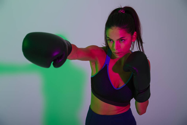 Beautiful strong fitness woman boxer isolated with led flash lights make boxing exercises. - Photo, Image