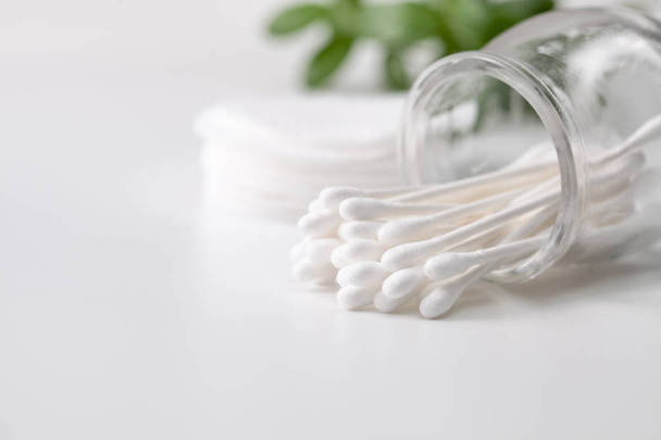 Cotton buds in a jar, cotton pads on a gray background. - Foto, afbeelding