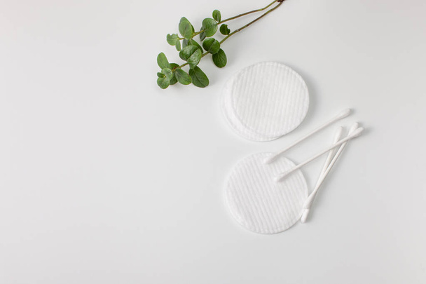 Cotton buds, cotton pads and a sprig of green on a gray background. - Foto, Imagen