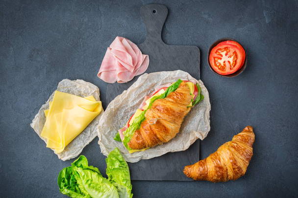 Kanapka ze świeżym rogalikiem z szynką, serem, sałatą i pomidorami - Zdjęcie, obraz