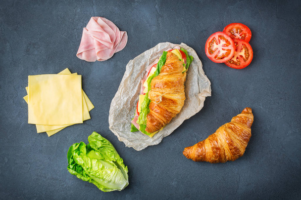 Σάντουιτς με φρέσκο κρουασάν με ζαμπόν, τυρί, μαρούλι και ντομάτα - Φωτογραφία, εικόνα