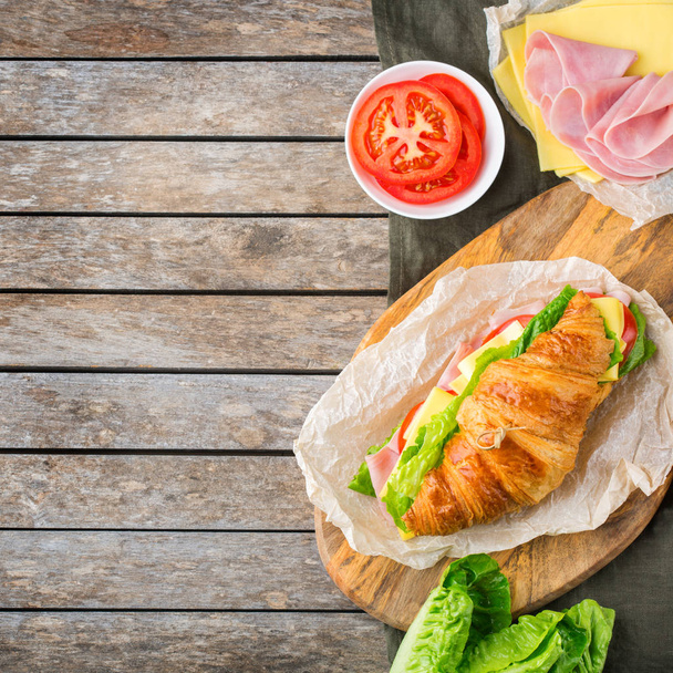 Свіжий бутерброд з круасанами з шинкою, сиром, салатом та помідорами
 - Фото, зображення