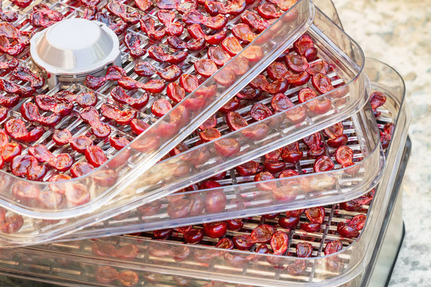 Kersen in de voedseldroger. Kersenhelften op dehydrator lade. Close-up, selectieve focus - Foto, afbeelding