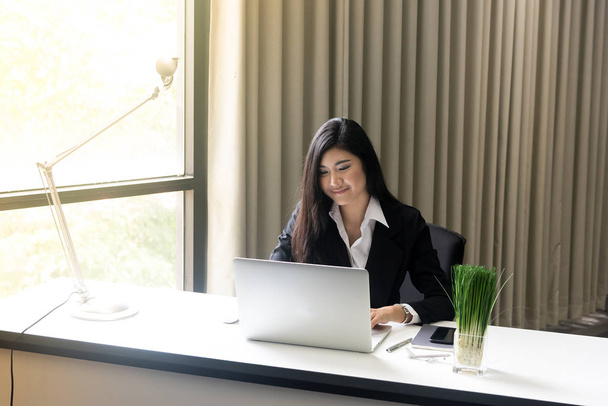 mooie zakelijke vrouw werken op haar laptop terwijl zittend op  - Foto, afbeelding