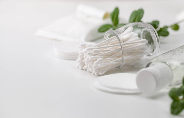 Cotton buds in a jar, cotton pads and a sprig of green  - Photo, Image