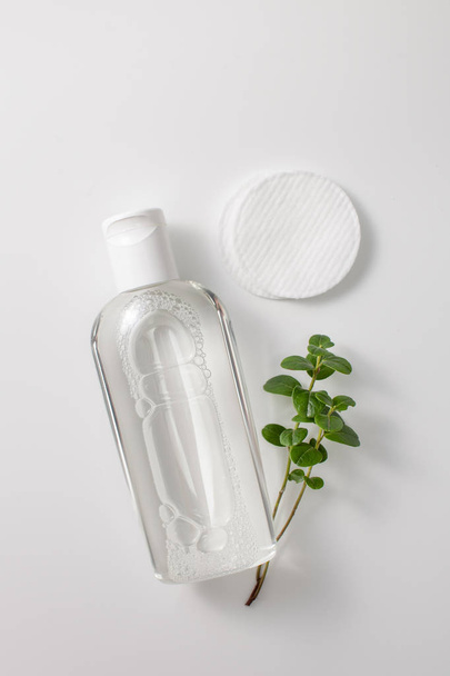 Micellar cleansing water in a bottle, cotton pads and a sprig of greenery - Photo, Image