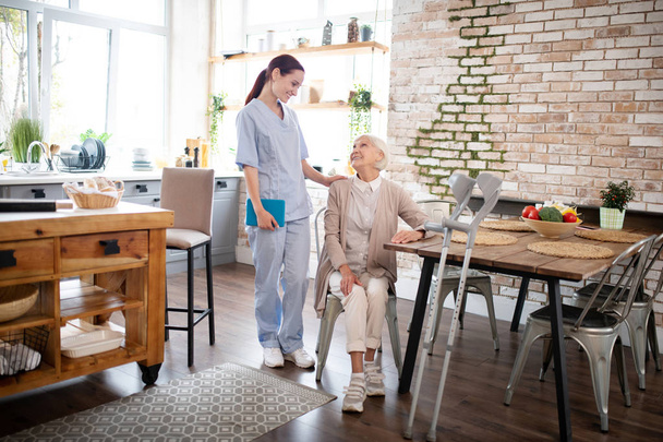 Caregiver in uniform coming to visit aged woman - Fotó, kép