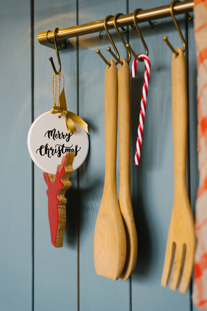 Kitchen wooden spatulas and fork Vit on a hook in the kitchen, cooking accessories, and Christmas tree toys for the New year - Photo, Image