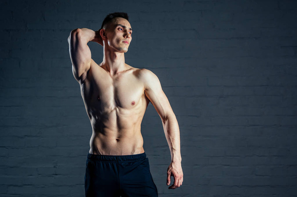 sexy naked man without clothes demonstrates the abs muscles on a dark background - Foto, Imagem