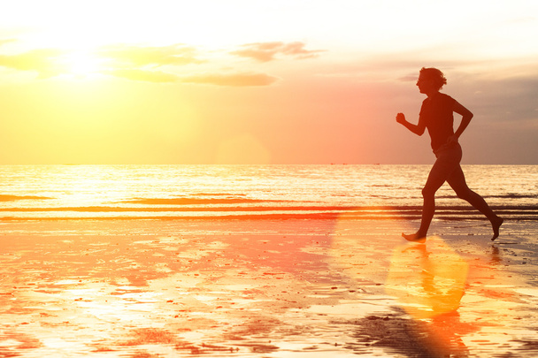 Jovem mulher correndo na praia ao pôr do sol
. - Foto, Imagem