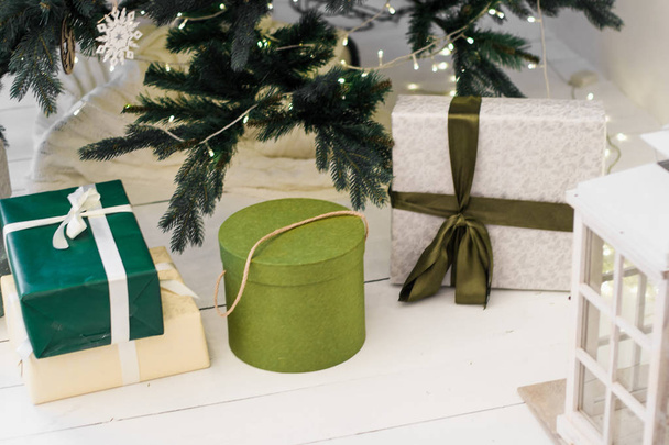 Noel tasarımları, hediye kutuları ve beyaz fenerler süslenmiş Noel ağacının altında duruyor.  - Fotoğraf, Görsel