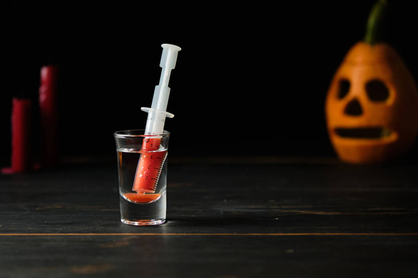 Blutiger Halloween-Cocktail und finstere Jack-Laterne auf dunklem Holztisch. - Foto, Bild